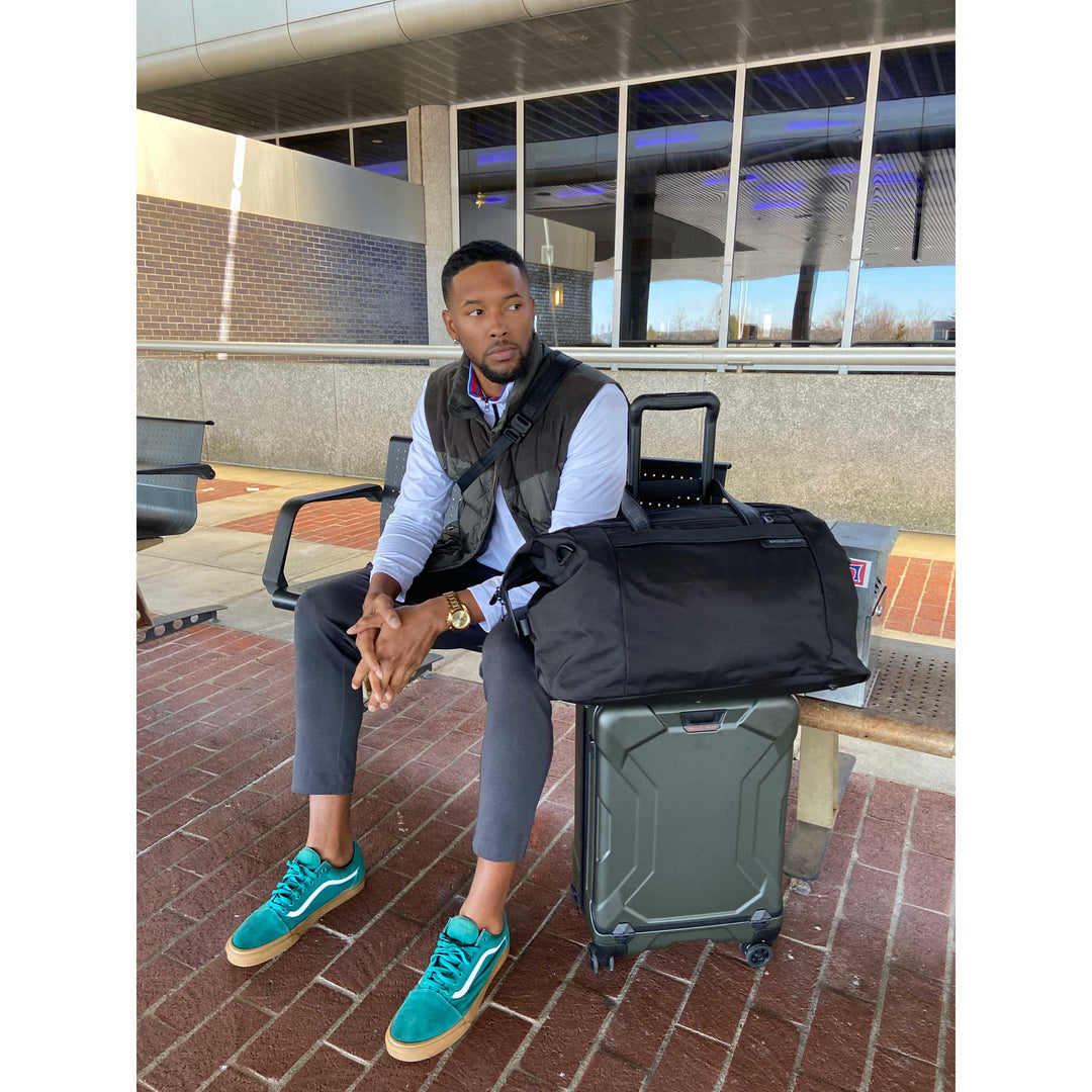 Man on bench waiting for taxi with green torq carry on luggage