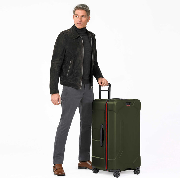 Man rolling extra large green hard shell luggage