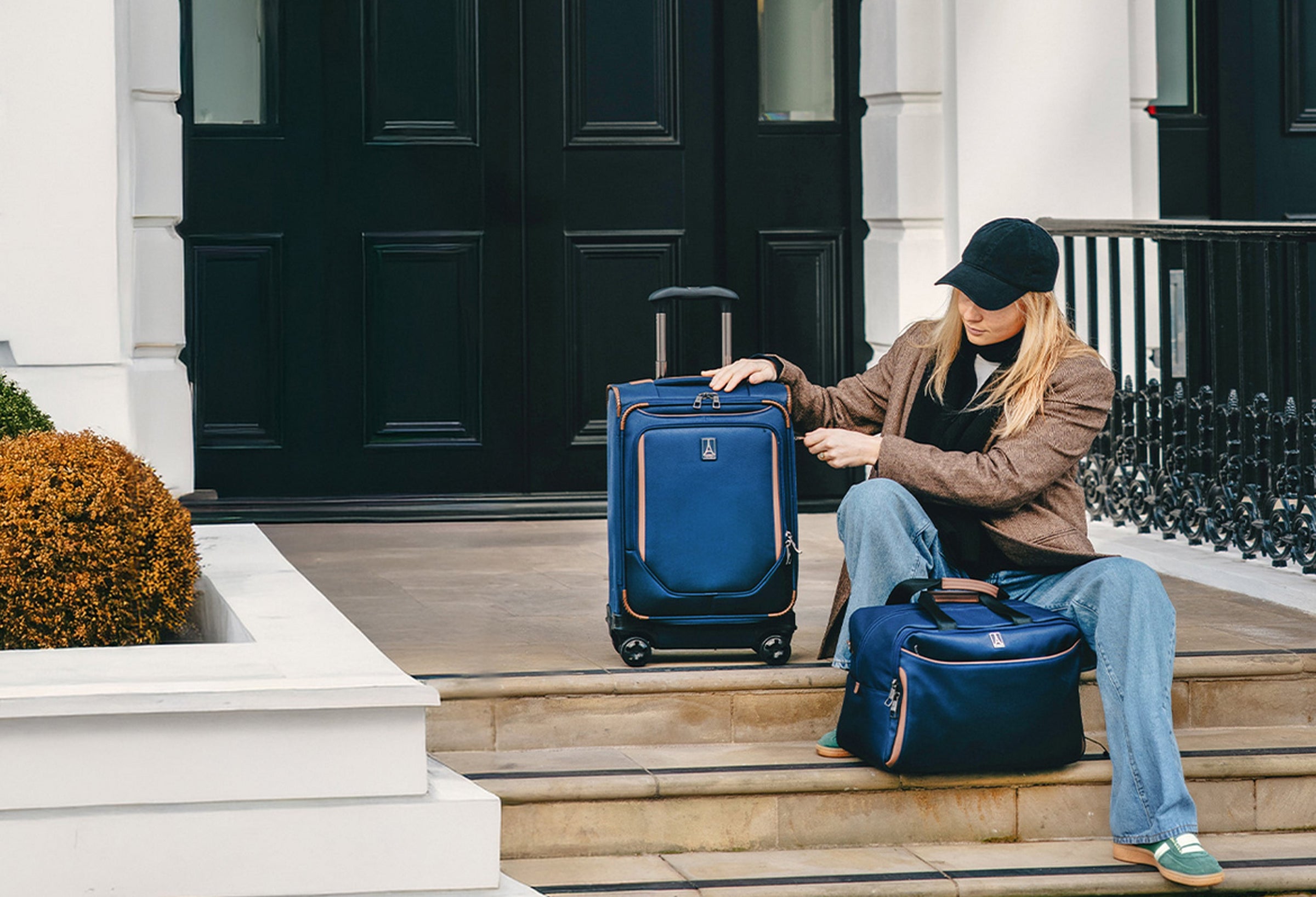 Woman sits on doorstep in redwood city, CA with luggage packed waiting for car to arrive