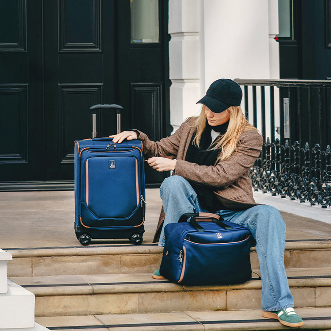 Woman sits on her front porch in Foster City, CA with her travelpro luggage waiting for car ride to airport