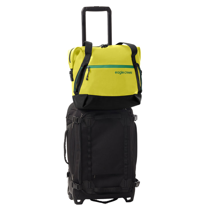 Eagle Creek Migrate Tote Bag color yellow sitting on wheeled duffel bag