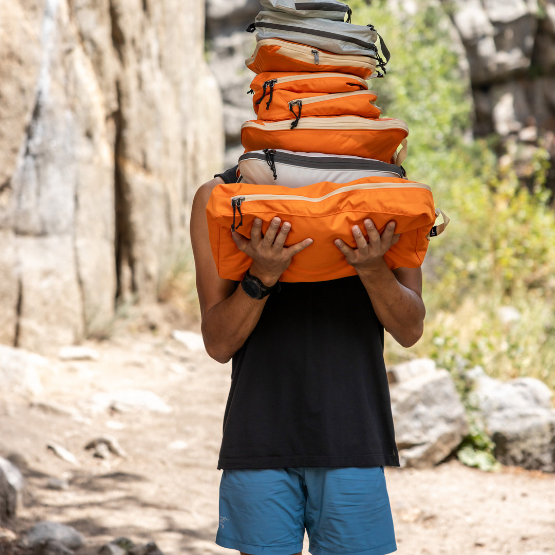 Hiker Holding a lot of bright orange packing cubes on hiking trail