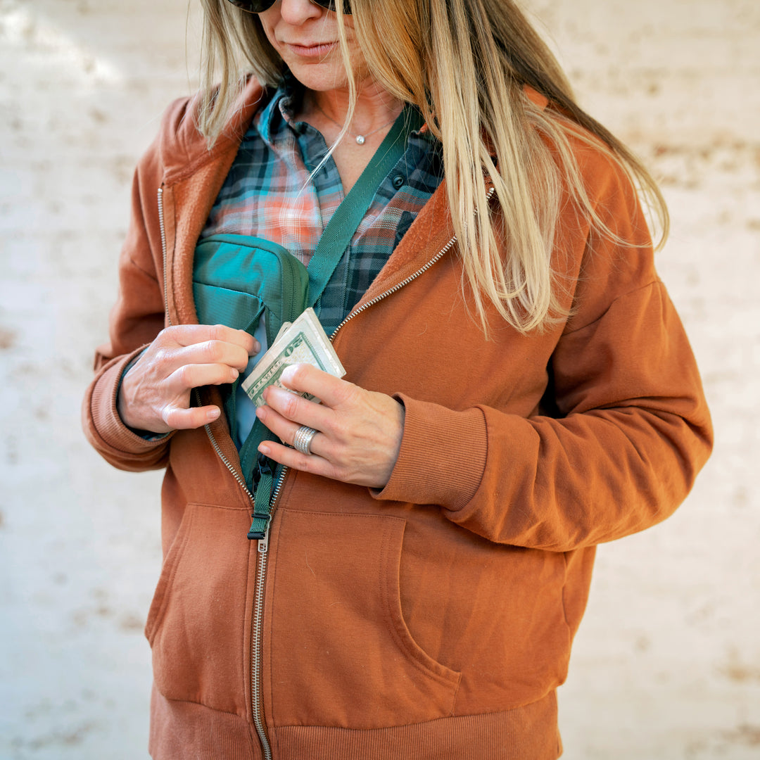 Woman wearing Eagle Creek Stash RFID Sling Bag under sweatshirt