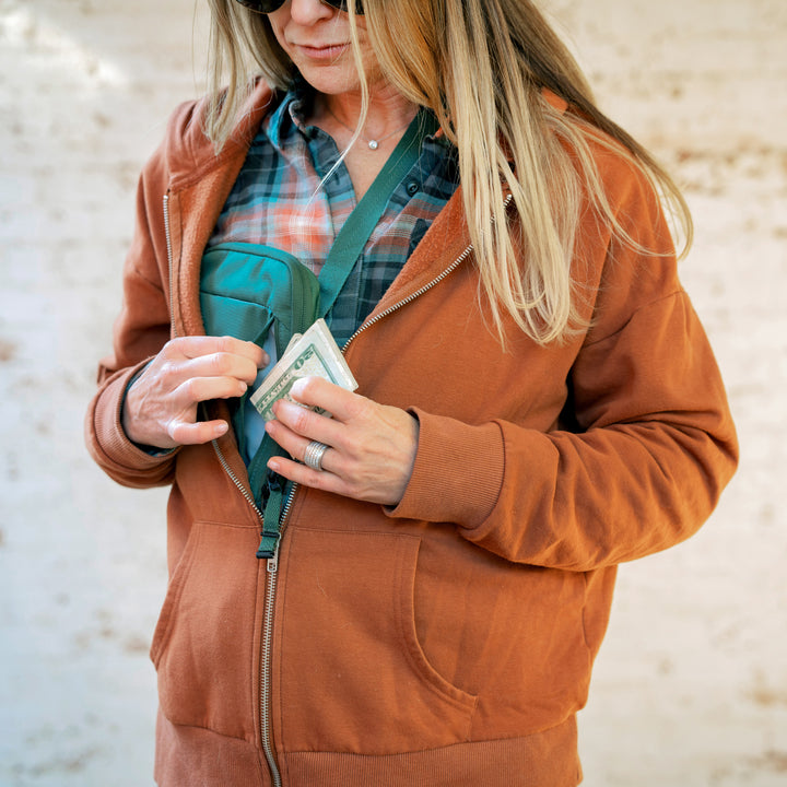 Woman wearing Eagle Creek Stash RFID Sling Bag under sweatshirt