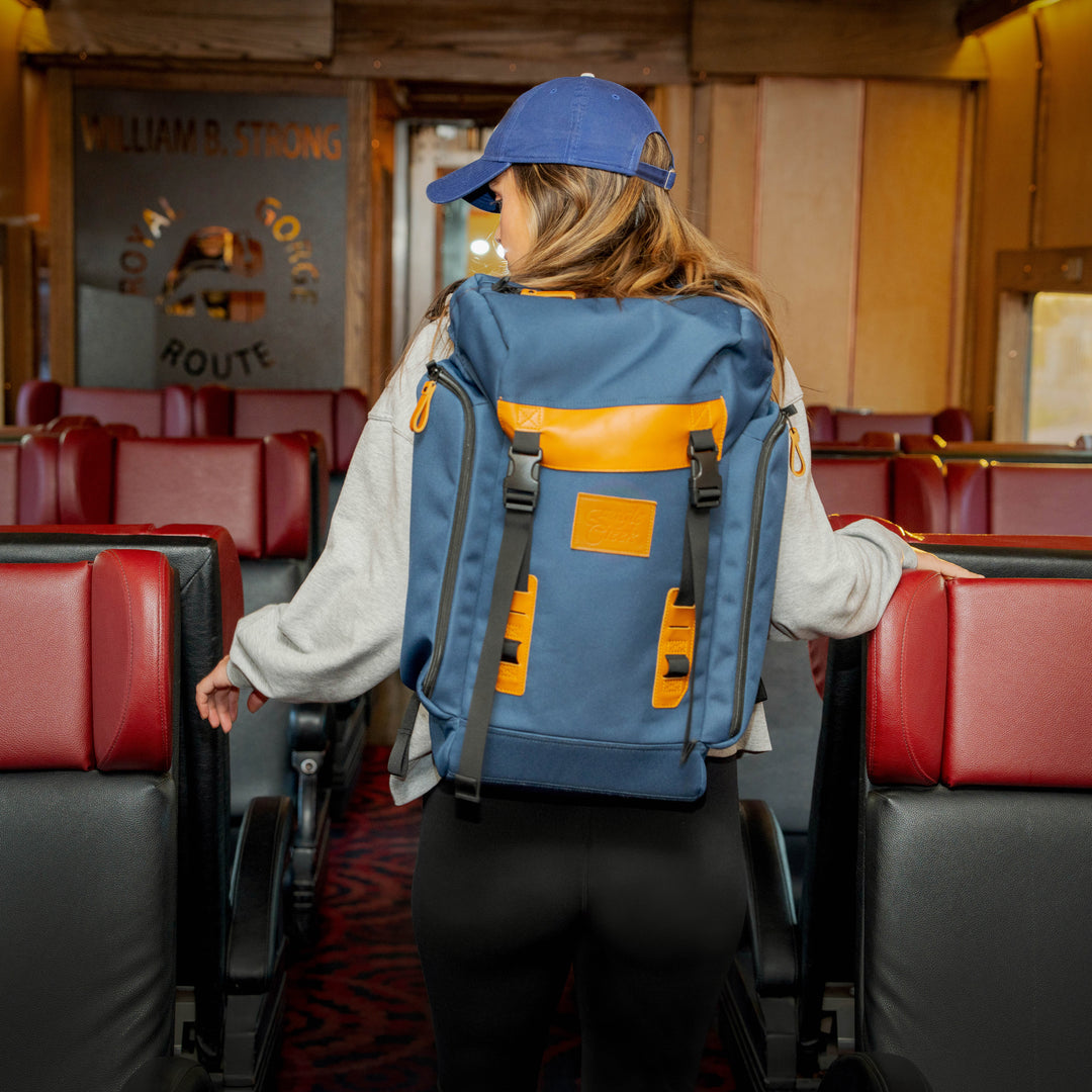 Woman wears Eagle Creek Origin Series Klettersack backpack on back while looking for her seat on a train