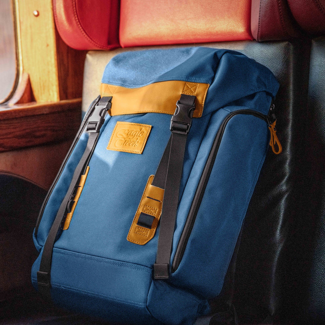 Close up of Eagle Creek Origin Series Klettersack backpack sitting on train seat with leather zipper pulls