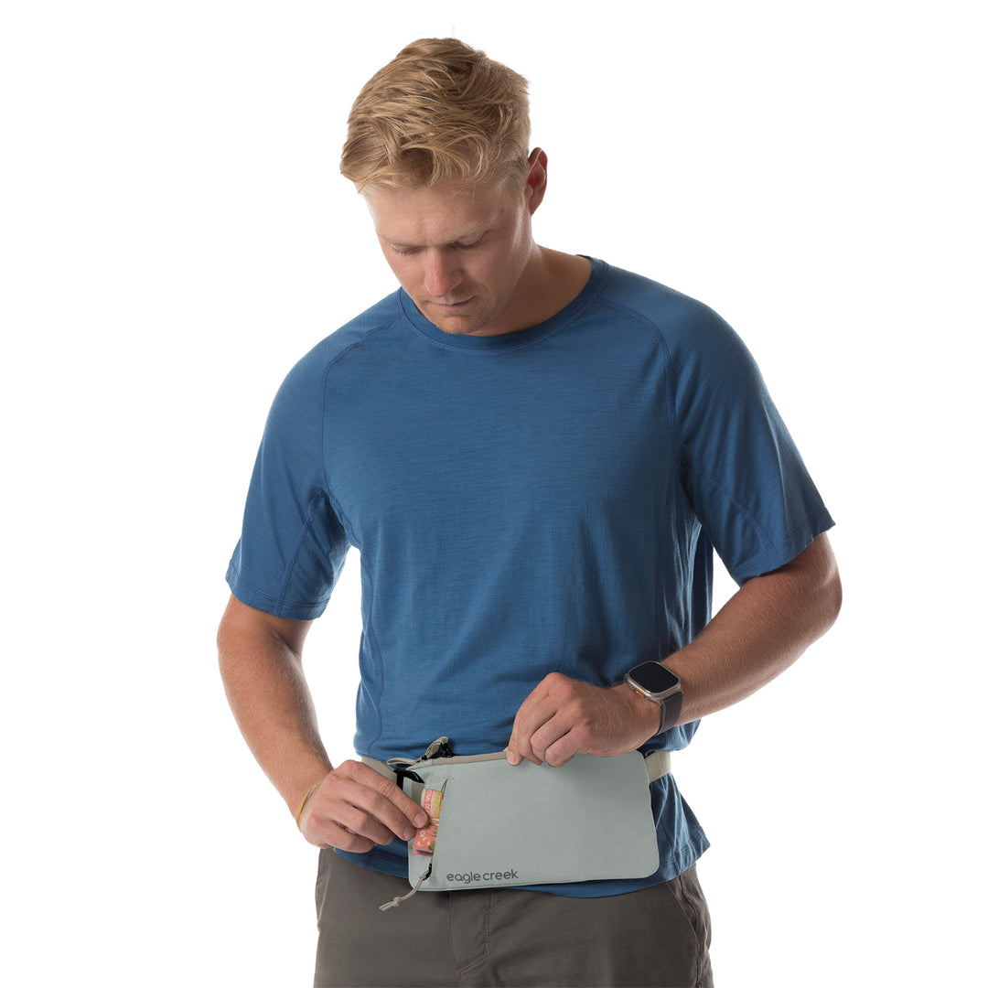 Man in blue shirt wearing Eagle Creek waist pack around waist with cash