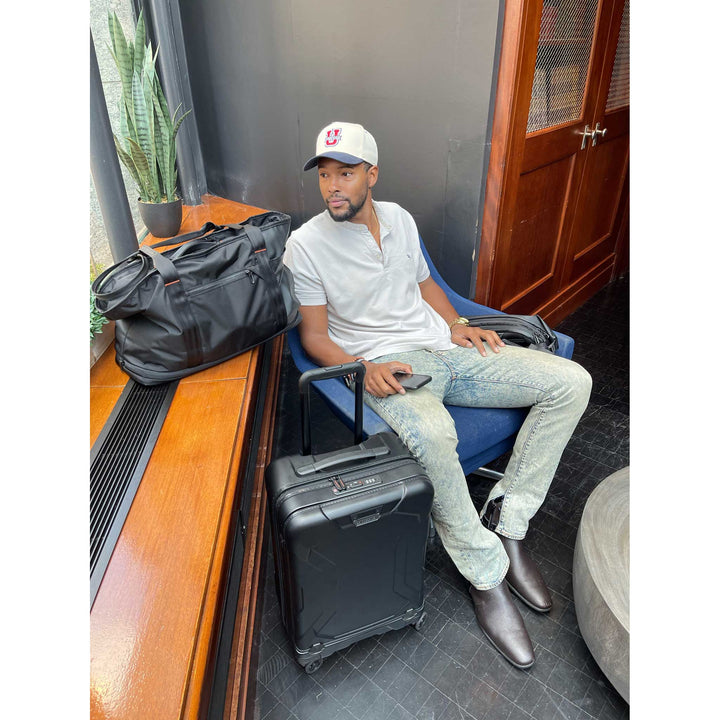 Man waiting in blue chair with torq hardshell carry on