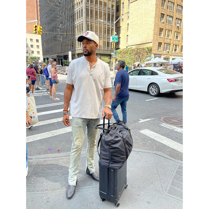 Man standing on busy nyc street corner with torq carry on