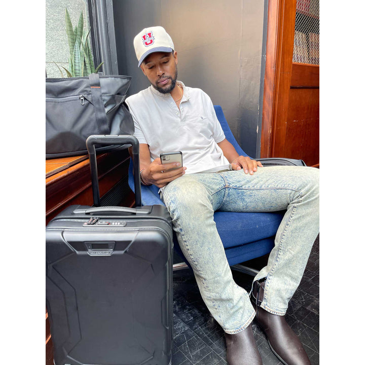 Man checking flight info with torq hardside domestic carry on suitcase