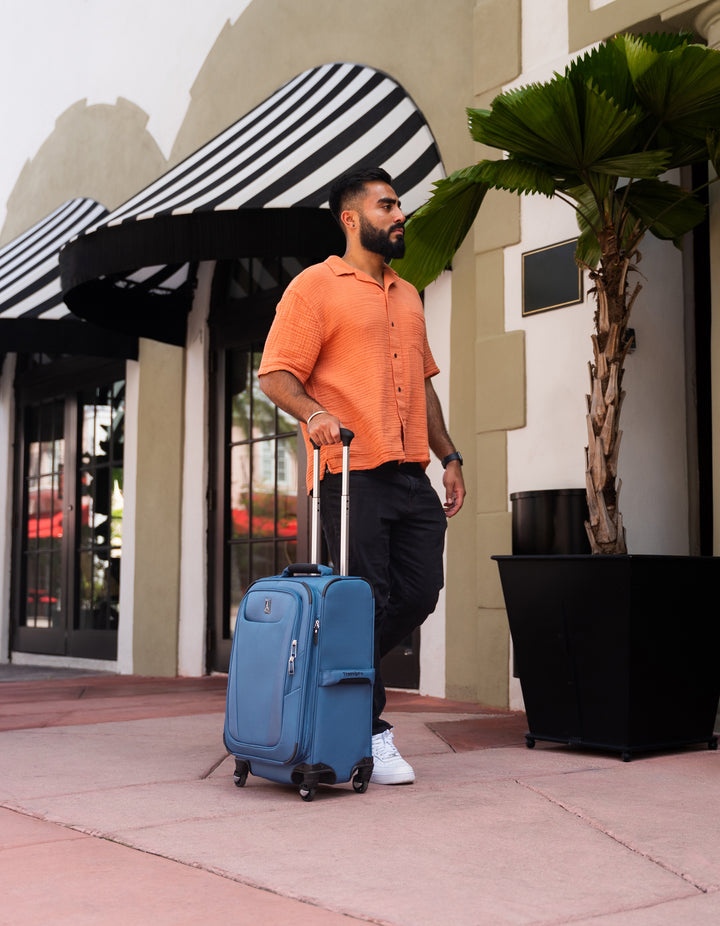 Man wheels his new TravelPro Maxlite® 5 Carry On Spinner in color blue through Stanford Shopping Mall stopping at a cafe
