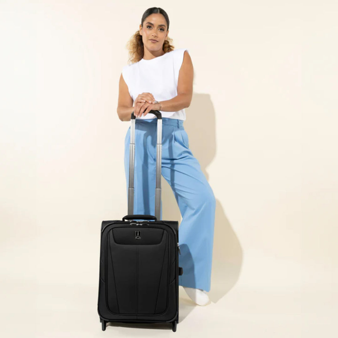 Woman stands with black TravelPro Maxlite® 5 International Carry On Rollaboard telescoping handle expanded