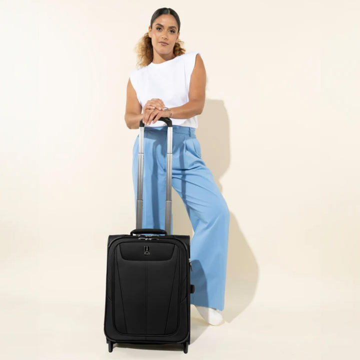 Woman stands with black TravelPro Maxlite® 5 International Carry On Rollaboard telescoping handle expanded